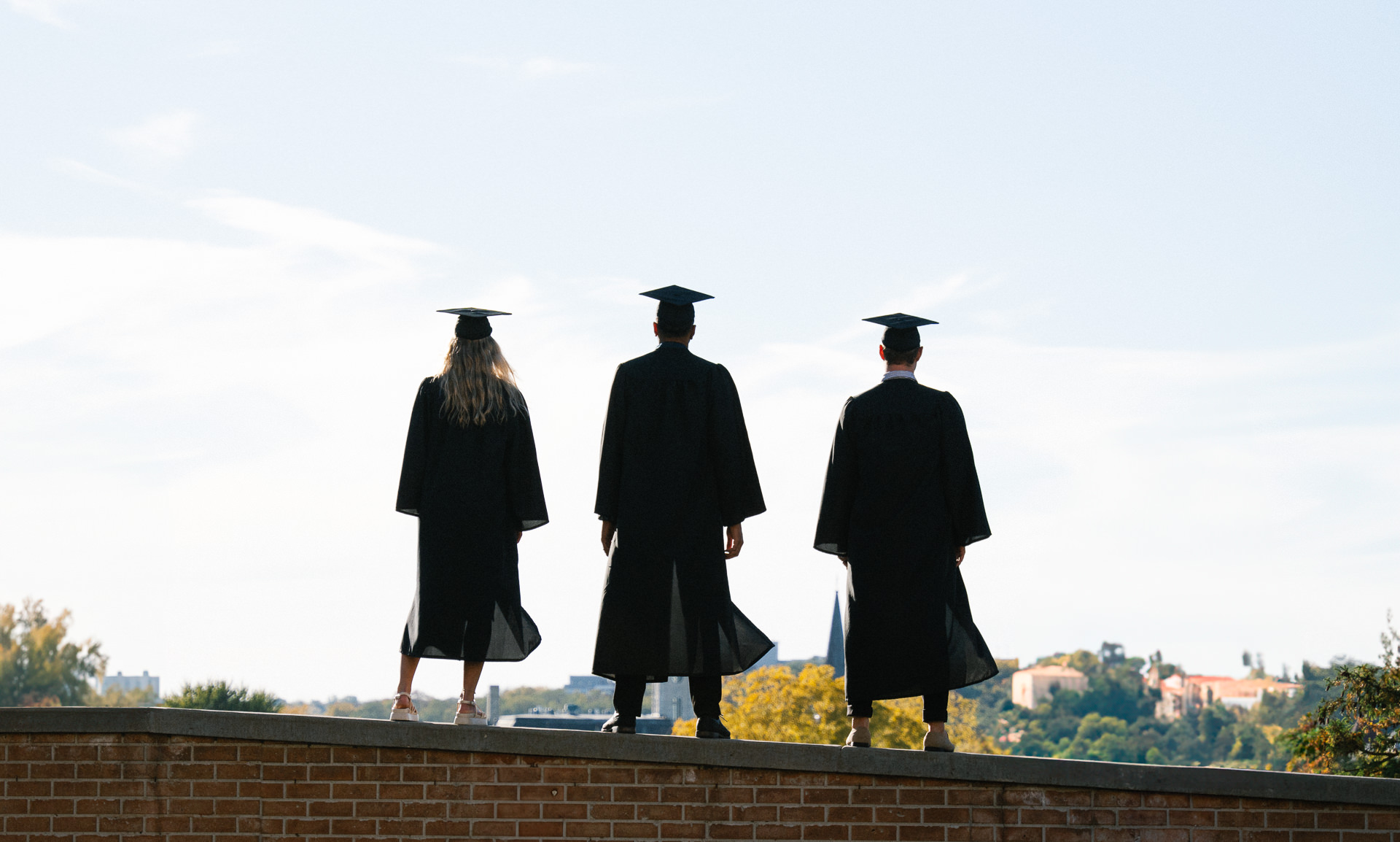 Three graduation students on a wall